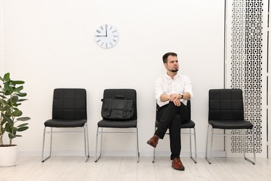 Photo of Man sitting on chair and waiting for job interview indoors