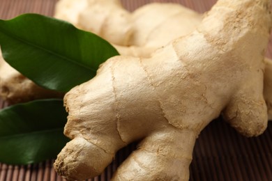 Fresh ginger with leaves on bamboo mat, closeup