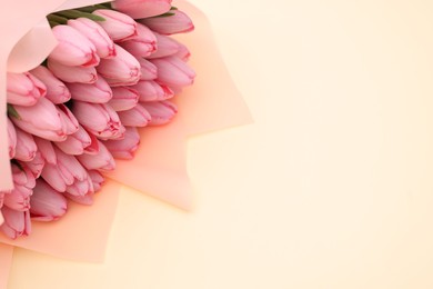 Photo of Bouquet of beautiful pink tulips on beige background, above view. Space for text