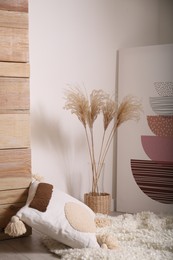 Photo of Vase with decorative dried plants and painting in stylish room interior