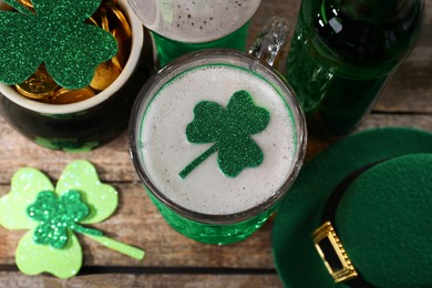 St. Patrick's day party. Green beer, leprechaun hat, pot of gold and decorative clover leaves on wooden table, above view