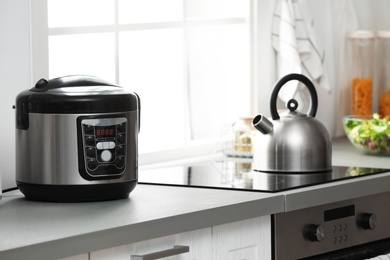 Photo of Modern electric multi cooker on kitchen countertop near stove
