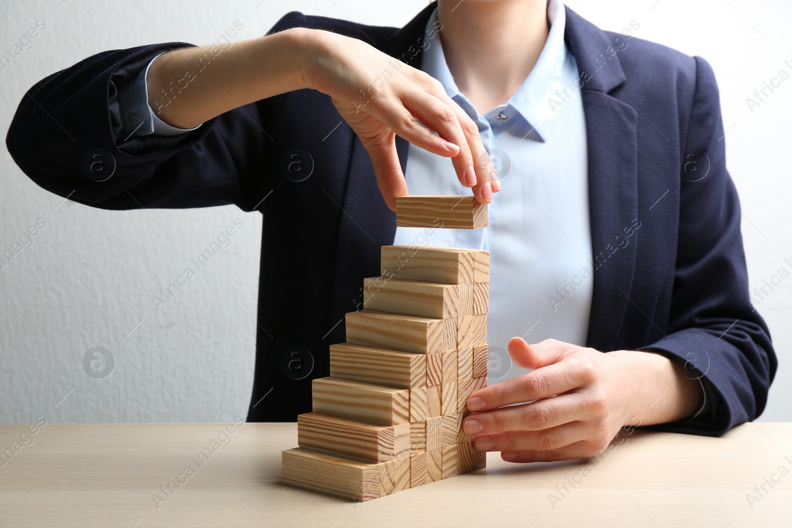 Photo of Woman building steps with wooden blocks at table, closeup. Career promotion concept
