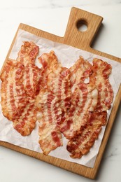 Photo of Delicious fried bacon slices on white marble table, top view