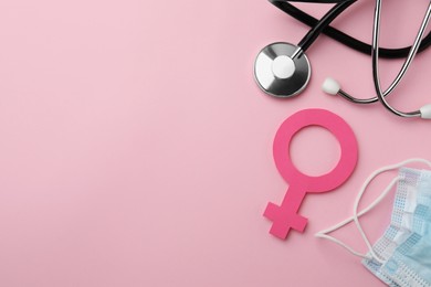 Photo of Female gender sign, stethoscope and facial mask on pink background, flat lay. Space for text