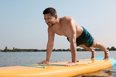 Man practicing yoga on SUP board on river