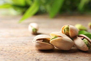Photo of Organic pistachio nuts on wooden table, closeup. Space for text