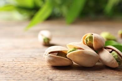 Organic pistachio nuts on wooden table, closeup. Space for text