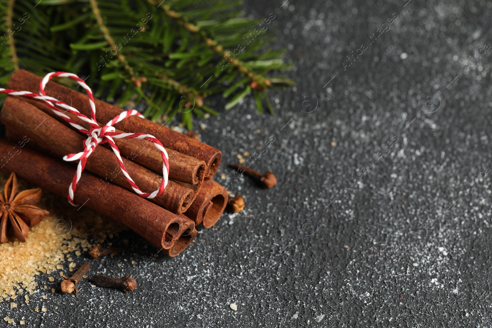 Photo of Different aromatic spices on grey textured table, closeup. Space for text