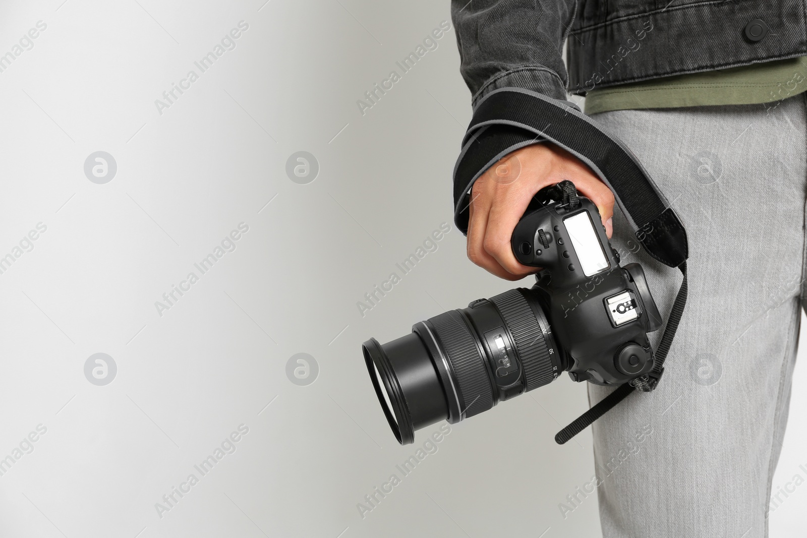 Photo of Professional photographer with modern camera on light background in studio, closeup