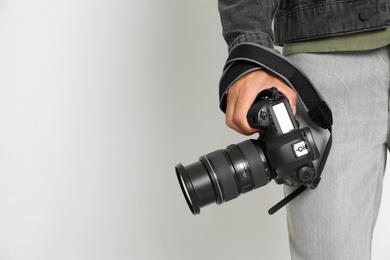 Photo of Professional photographer with modern camera on light background in studio, closeup