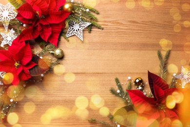 Flat lay composition with traditional Christmas poinsettia flowers and space for text on wooden table, bokeh effect