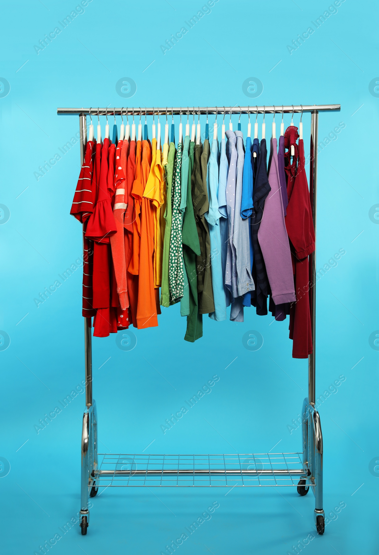 Photo of Wardrobe rack with different bright clothes on color background