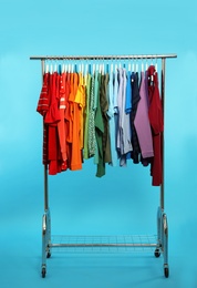 Photo of Wardrobe rack with different bright clothes on color background