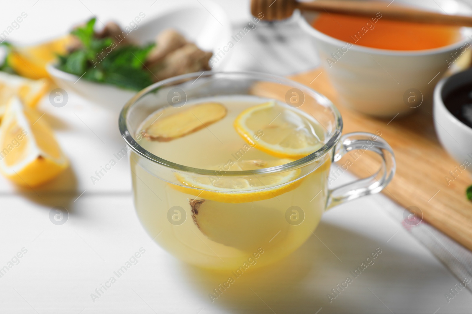 Photo of Delicious ginger tea and ingredients on white wooden table