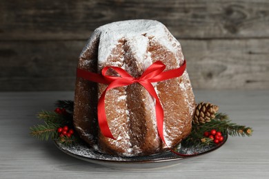 Delicious Pandoro cake with powdered sugar and red bow, Christmas decor on white wooden table. Traditional Italian pastry