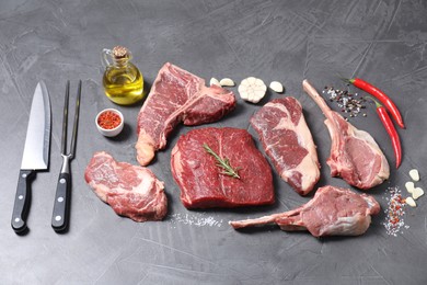 Photo of Fresh raw beef cuts, spices and butcher tools on light grey textured table, above view