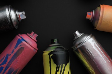 Photo of Used cans of spray paints on black background, flat lay with space for text. Graffiti supplies