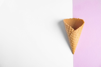 Photo of Empty wafer ice cream cone on color background, top view. Space for text