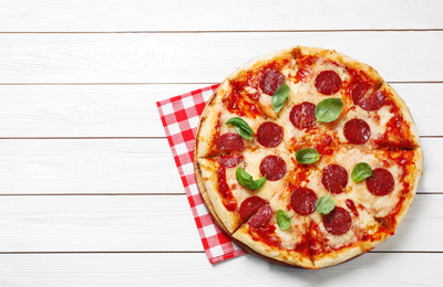 Photo of Hot delicious pepperoni pizza on white wooden table, top view. Space for text