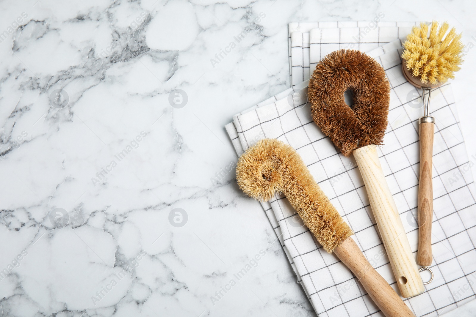 Photo of Cleaning brushes on white marble table, flat lay with space for text. Dish washing supplies