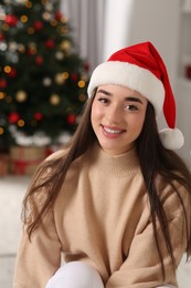 Photo of Beautiful woman wearing red Christmas hat indoors