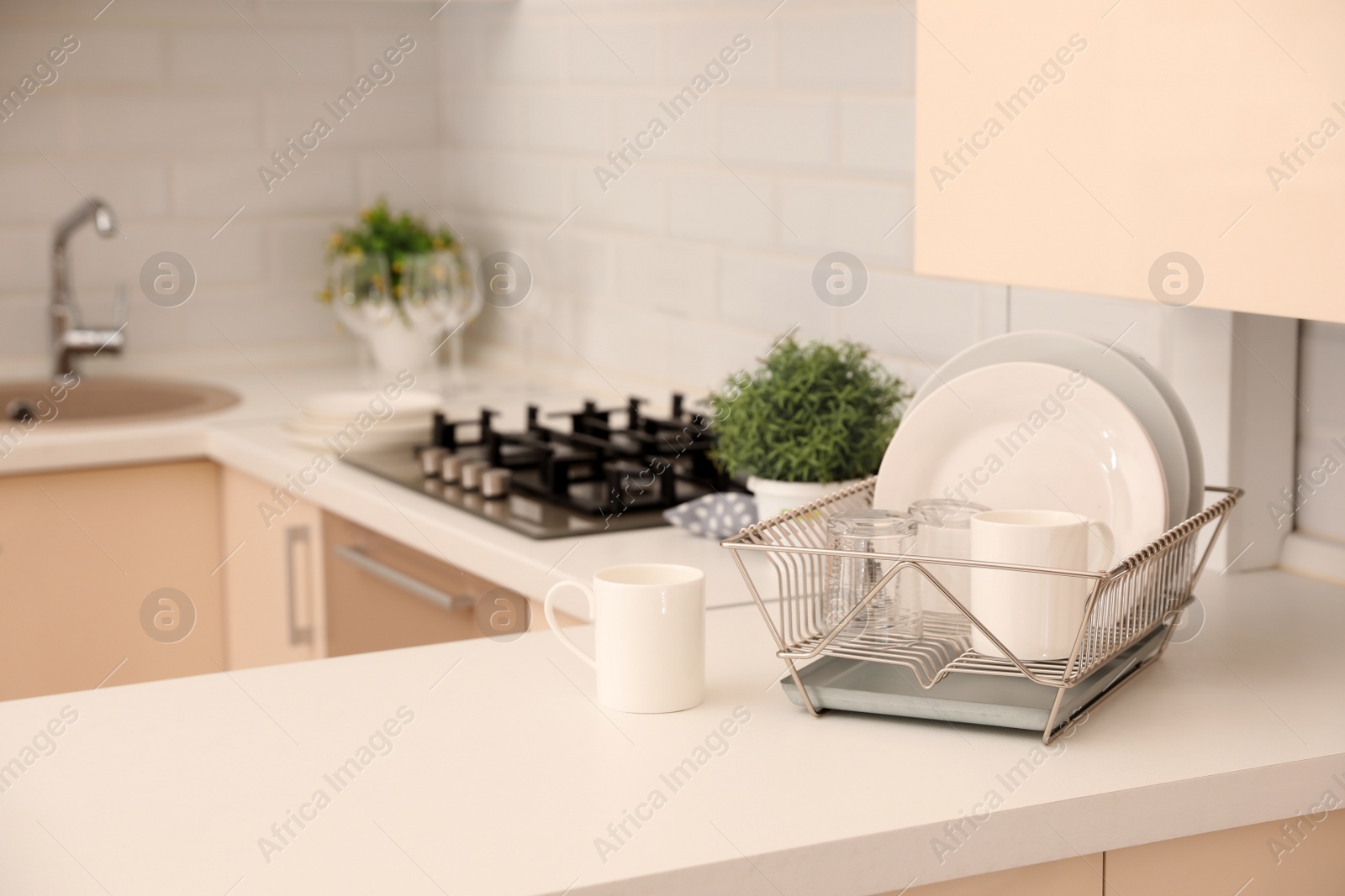 Photo of Dish drainer with clean dinnerware on table in kitchen. Space for text