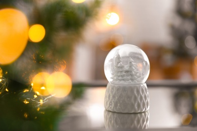 Photo of Decorative Christmas snow globe on mirror surface