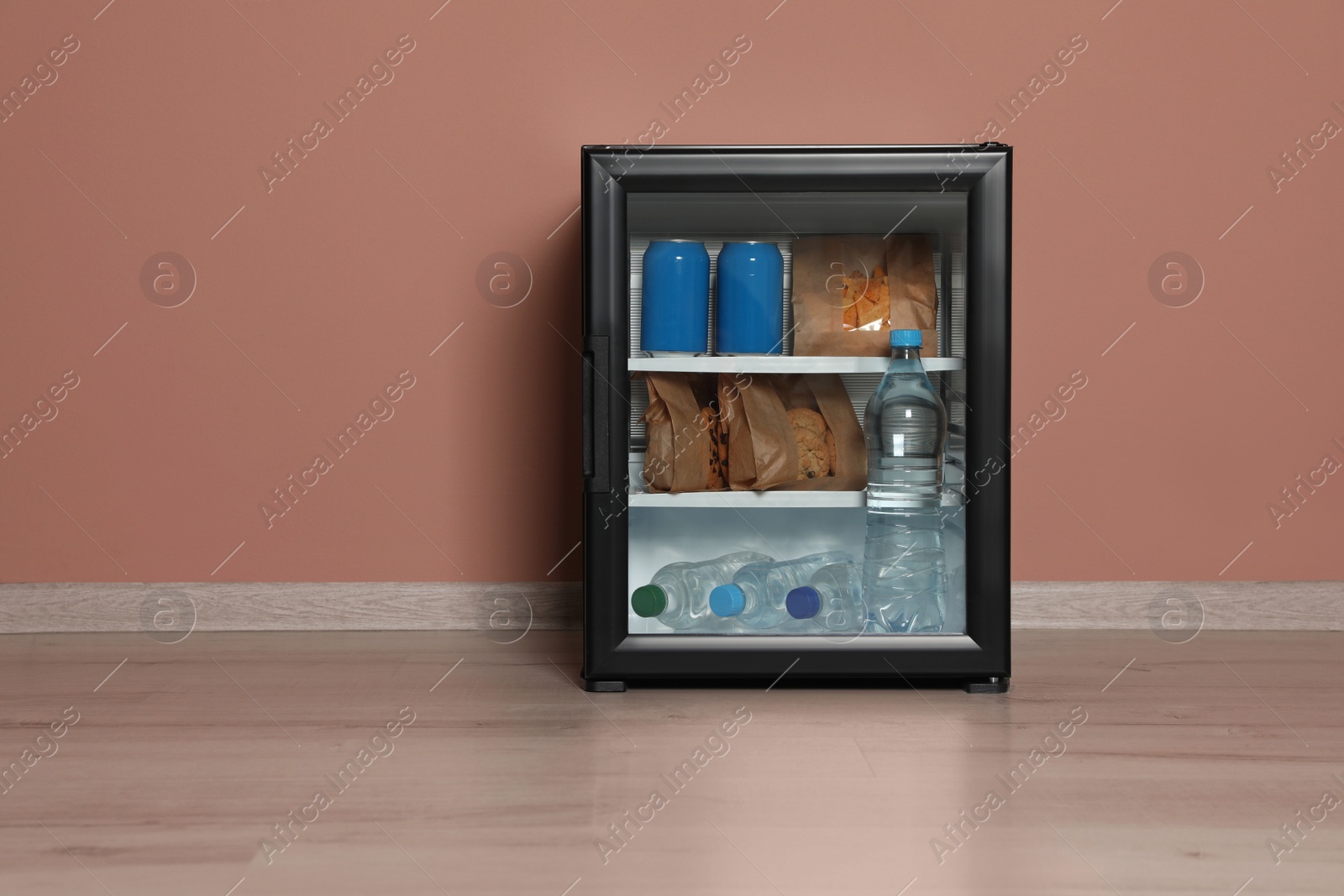 Photo of Mini bar filled with food and drinks near pale pink wall indoors, space for text