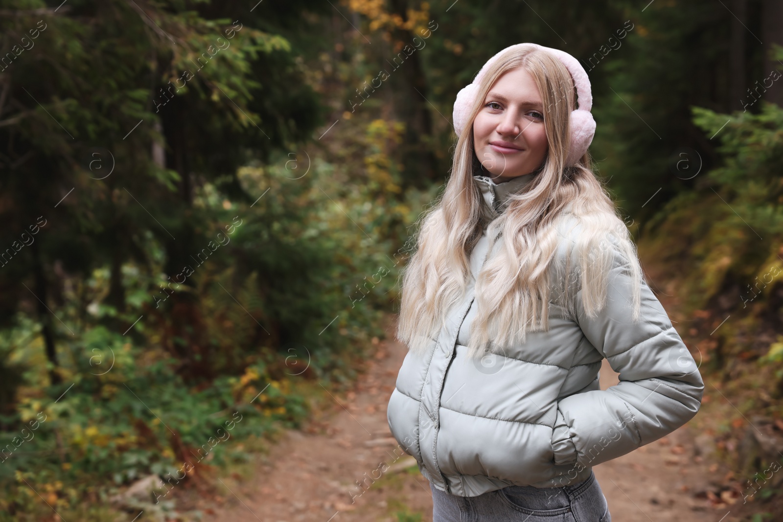 Photo of Young beautiful woman wearing warm earmuffs in forest