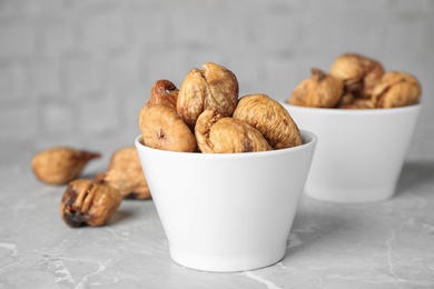 Photo of Bowls of tasty dried figs on light grey marble table