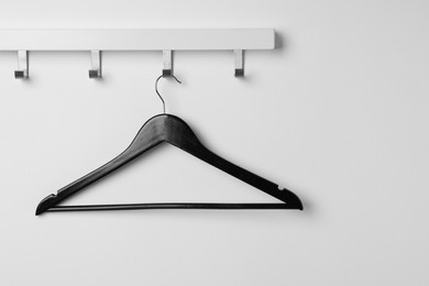 Photo of Rack with empty black clothes hanger on white wall