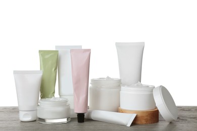 Photo of Set of cosmetic products in jars and tubes on wooden table against white background
