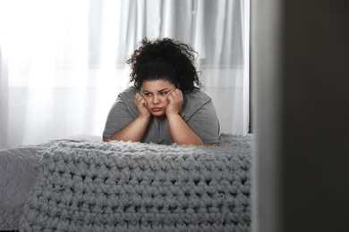 Photo of Depressed overweight woman on bed at home