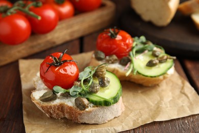 Photo of Tasty bruschettas with vegetables and capers served on wooden table, closeup