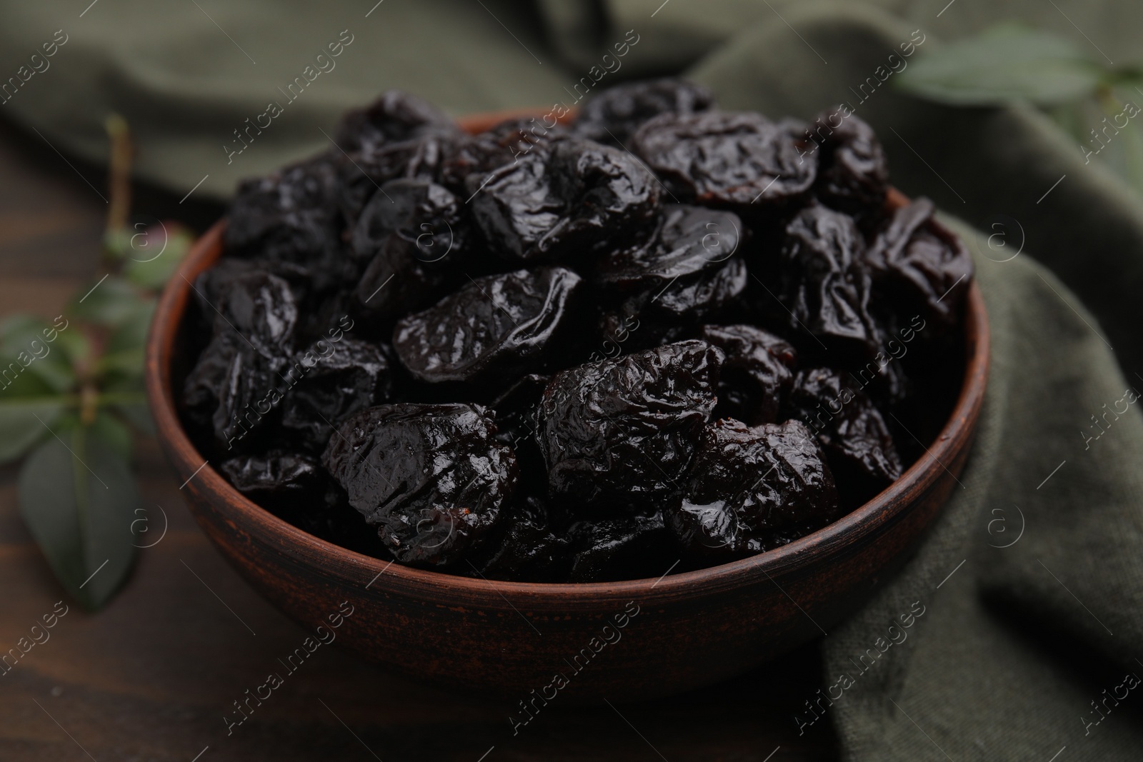 Photo of Sweet dried prunes in bowl on table, closeup