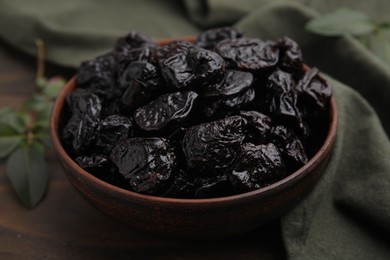 Sweet dried prunes in bowl on table, closeup