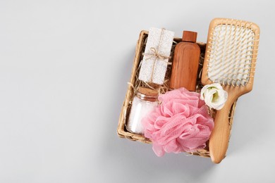 Photo of Spa gift set with different products in wicker box on light grey background, top view. Space for text
