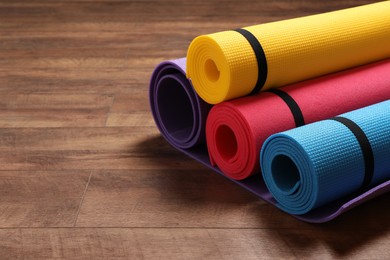 Photo of Bright rolled camping mats on wooden background. Space for text