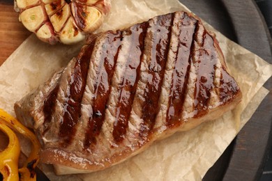 Delicious grilled beef steak with garlic on table, top view