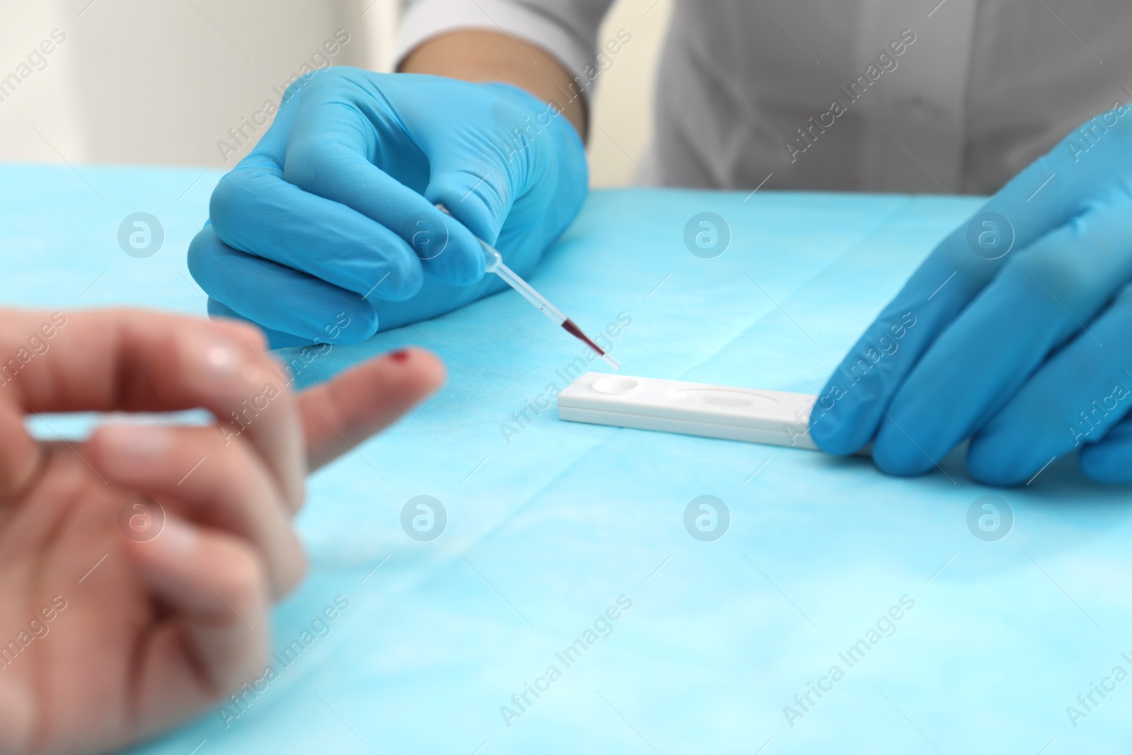 Photo of Doctor testing blood sample from patient's finger at table, closeup