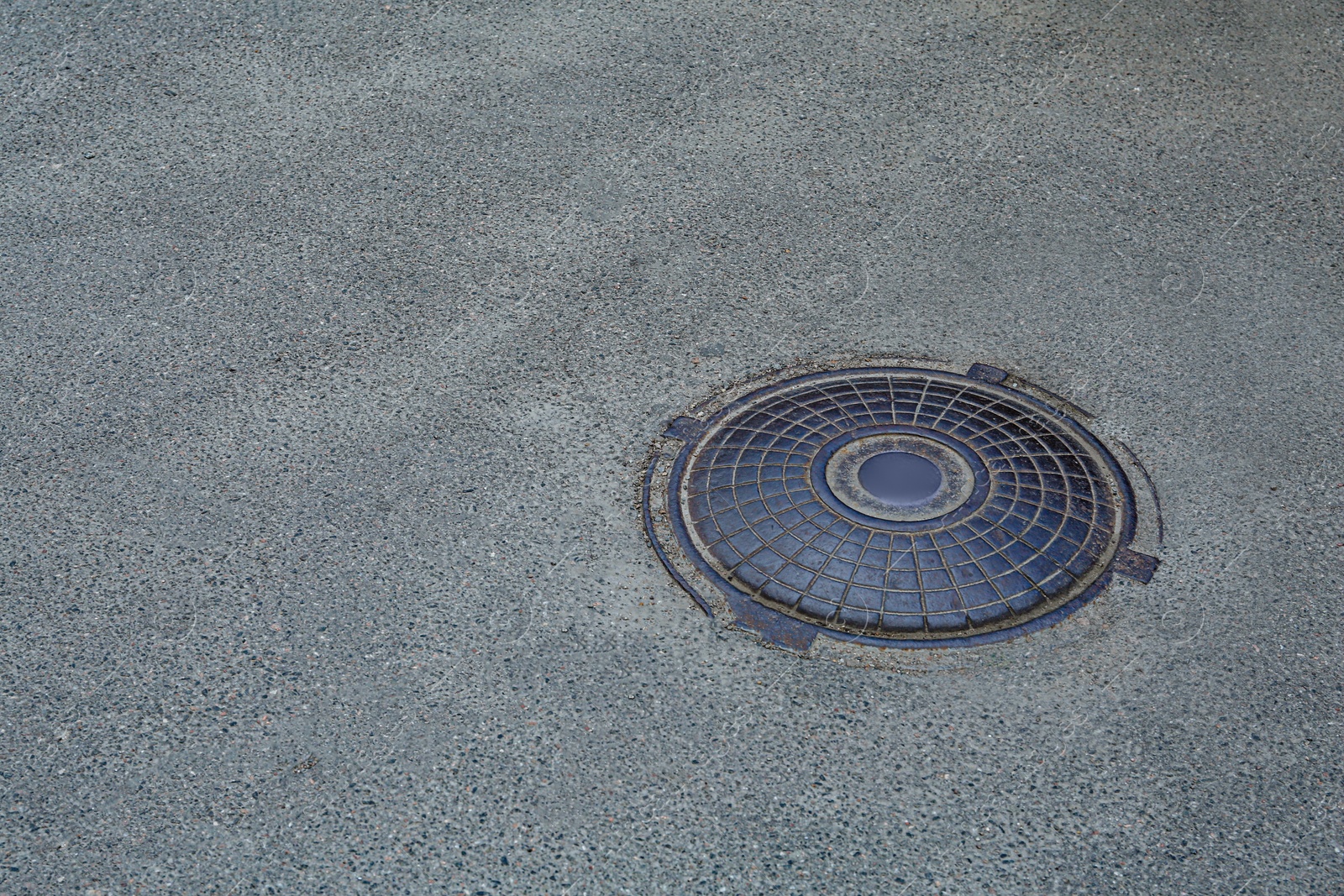 Photo of Metal sewer hatch on asphalt outdoors, space for text