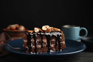 Photo of Piece of tasty homemade chocolate cake with nuts on black table, closeup. Space for text
