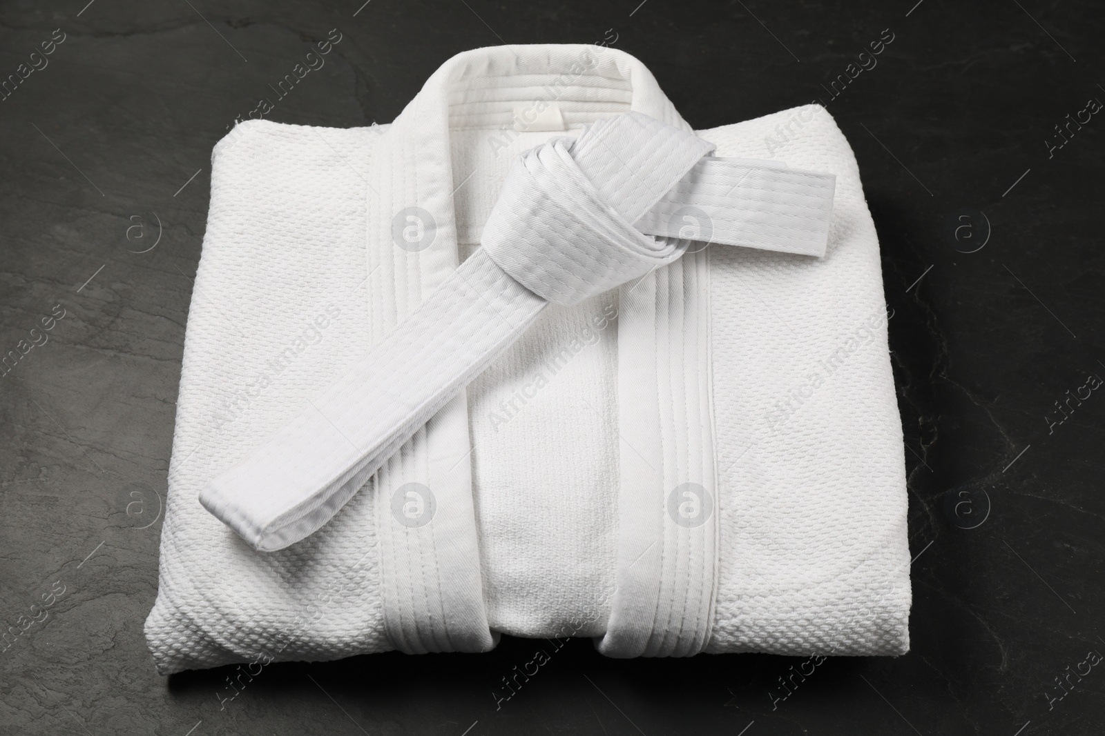 Photo of White karate belt and kimono on gray background