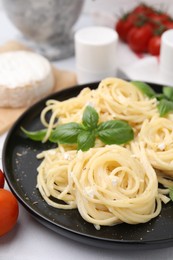 Photo of Delicious pasta with brie cheese and basil leaves on white table, closeup