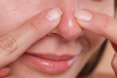 Photo of Woman popping pimple on her nose, closeup