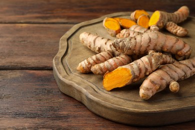 Photo of Many fresh turmeric roots on wooden table, closeup. Space for text