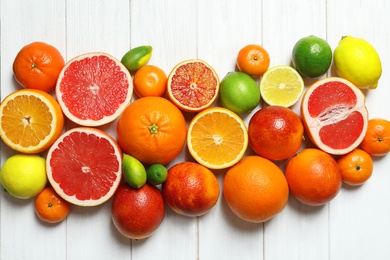 Flat lay composition with different citrus fruits on white wooden background