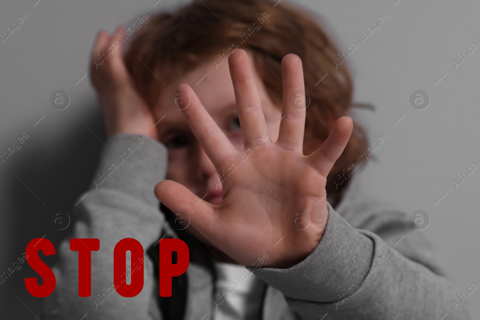 Image of No child abuse. Boy making stop gesture near grey wall, selective focus