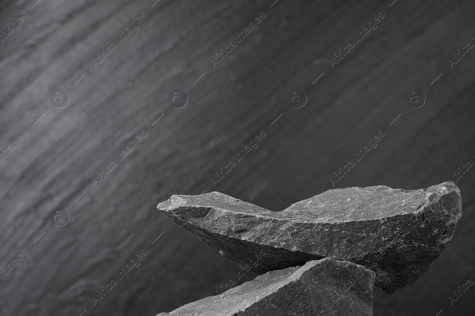 Photo of Presentation for product. Podium made of stones on grey textured background. Space for text